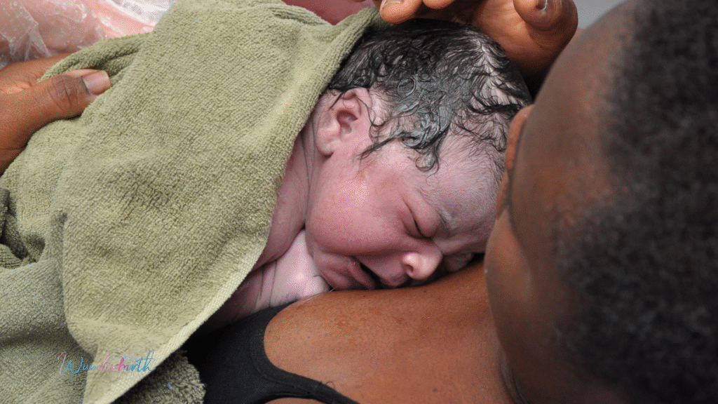 A new mother holding her newborn in a birth pool, showing another positive home water birth outcome.